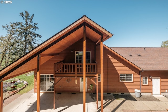 back of property with crawl space, a patio area, and a shingled roof