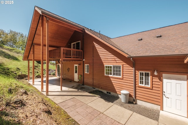 rear view of house with roof with shingles and a patio