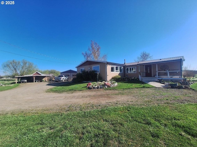 back of house featuring a lawn and dirt driveway
