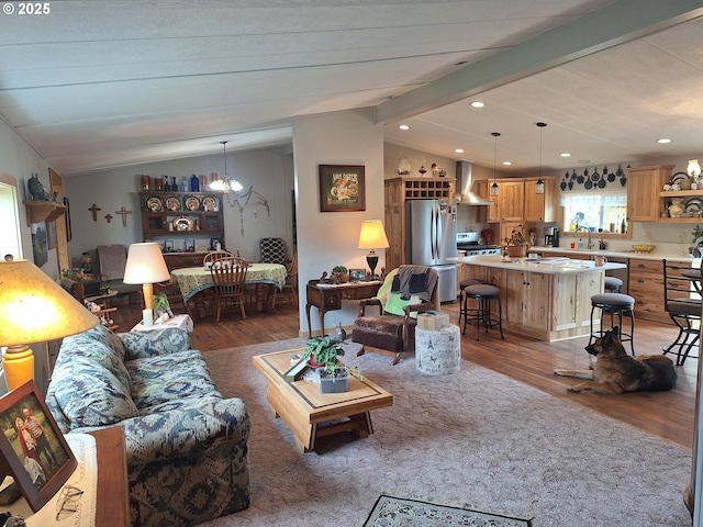 living area with vaulted ceiling with beams, recessed lighting, wood finished floors, and a notable chandelier