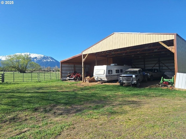 exterior space with a lawn, a detached carport, a mountain view, and fence