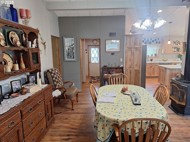 dining space featuring beamed ceiling, a wood stove, light wood-style flooring, and a chandelier