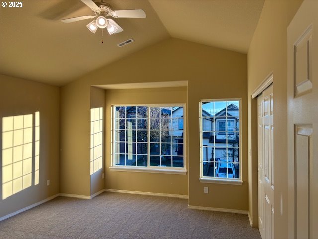 unfurnished bedroom featuring dark carpet, lofted ceiling, ensuite bathroom, ceiling fan, and a closet