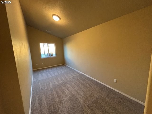 carpeted spare room featuring vaulted ceiling