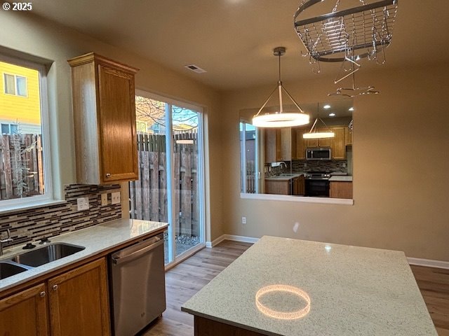 kitchen featuring pendant lighting, sink, tasteful backsplash, light hardwood / wood-style floors, and stainless steel appliances