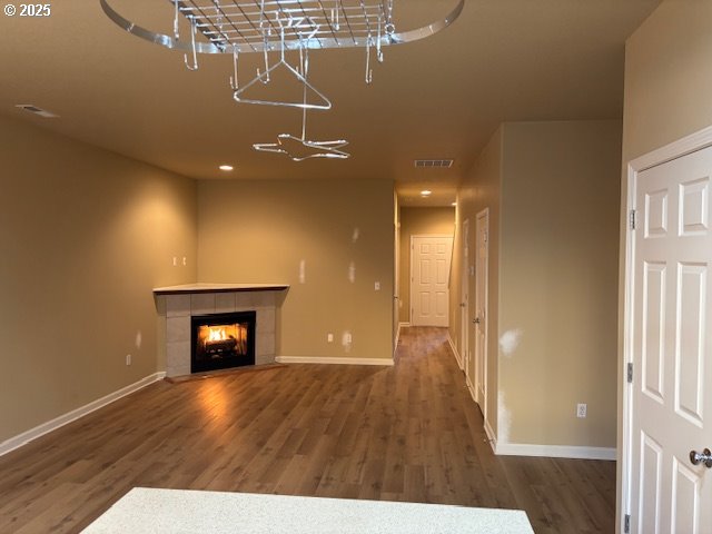 unfurnished living room featuring dark wood-type flooring and a tile fireplace