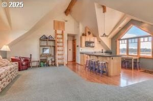52995 Riverview Dr, La Pine, OR 97739 - kitchen with stainless steel microwave, a breakfast bar area, open floor plan, and wood finished floors