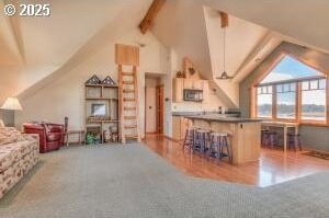 interior space with lofted ceiling with beams, stainless steel microwave, and carpet