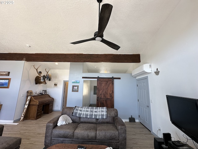 living room featuring an AC wall unit, a barn door, a textured ceiling, and beam ceiling