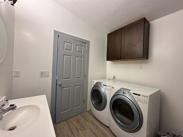 laundry room with separate washer and dryer, a sink, light wood-style flooring, and a textured ceiling