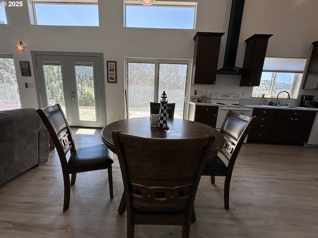 dining room featuring plenty of natural light, wood finished floors, and a towering ceiling