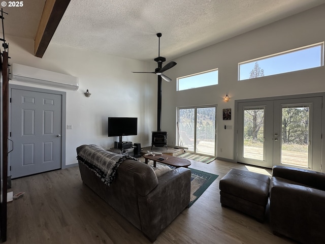 living room featuring a wood stove, a textured ceiling, ceiling fan, and wood finished floors
