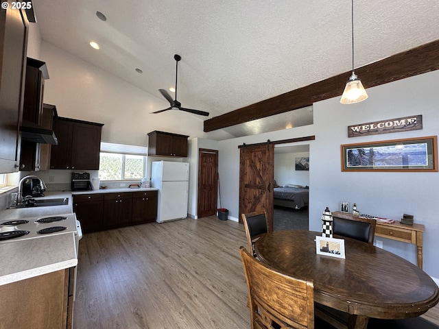 kitchen with a barn door, a sink, range with electric cooktop, freestanding refrigerator, and a ceiling fan