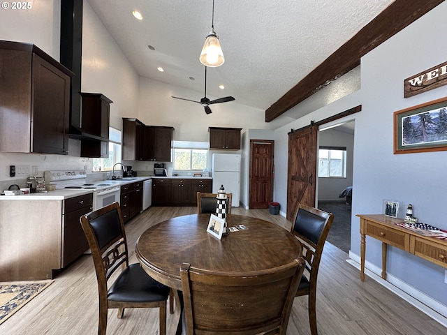 dining area with a barn door, a textured ceiling, a ceiling fan, and light wood-style flooring