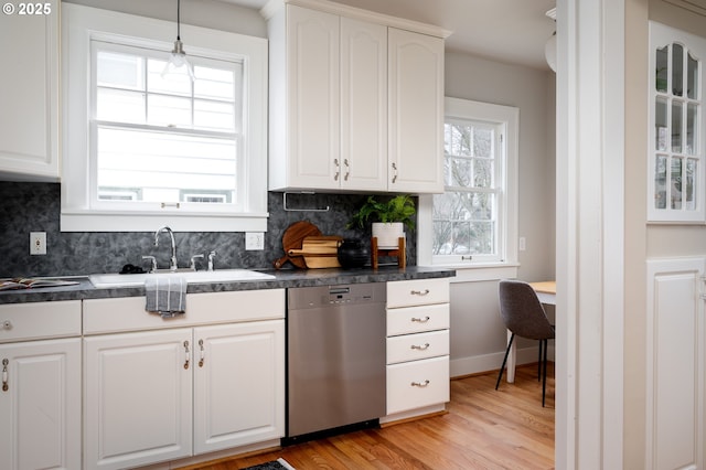 kitchen with tasteful backsplash, dishwasher, sink, and white cabinetry