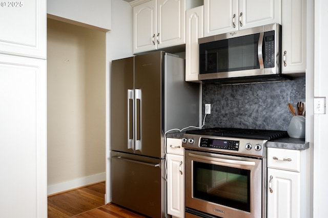 kitchen featuring wood-type flooring, backsplash, white cabinetry, and stainless steel appliances