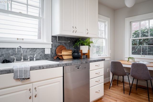 kitchen with white cabinetry, tasteful backsplash, stainless steel dishwasher, light hardwood / wood-style flooring, and sink