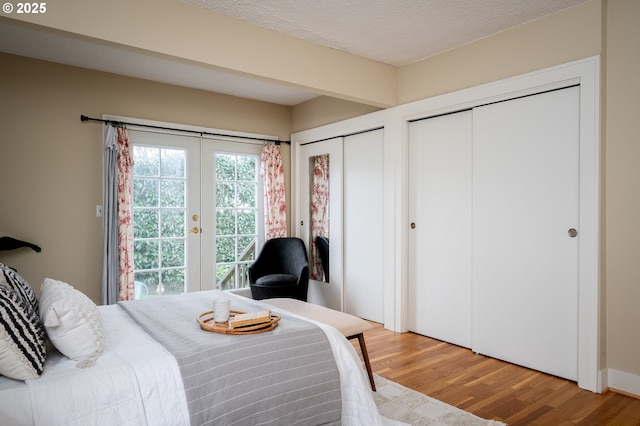 bedroom featuring two closets, a textured ceiling, and hardwood / wood-style flooring