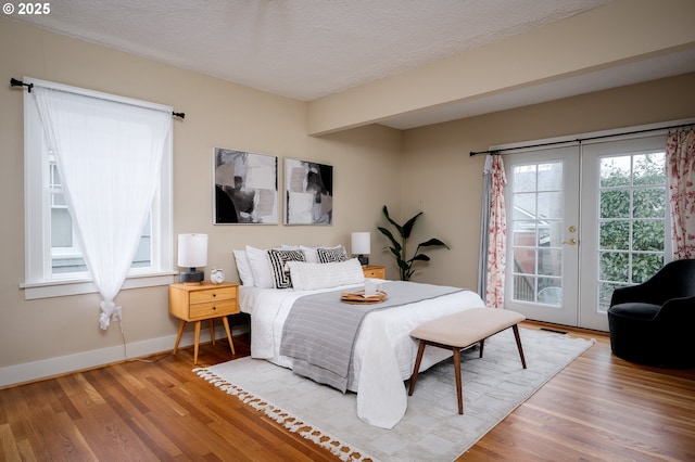 bedroom with hardwood / wood-style flooring, a textured ceiling, access to outside, and french doors