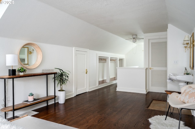 living area featuring vaulted ceiling, ceiling fan, a textured ceiling, and dark hardwood / wood-style floors