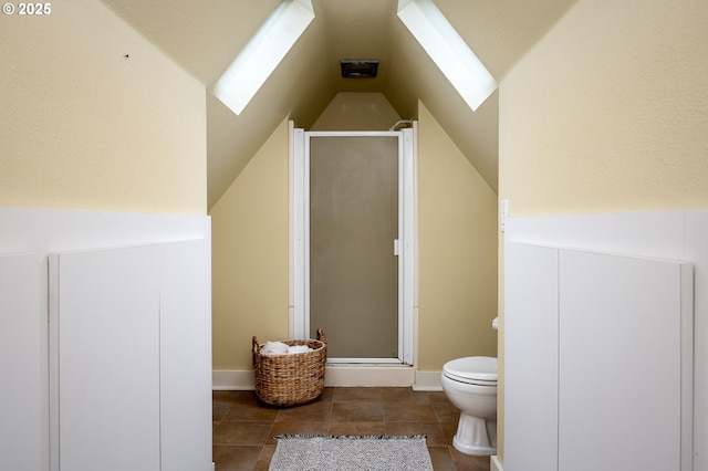 bathroom featuring toilet, vaulted ceiling with skylight, and a shower with door