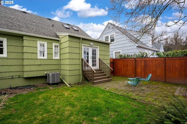 rear view of house with a lawn, cooling unit, and a patio area