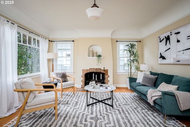 living room with wood-type flooring, ornamental molding, and a fireplace