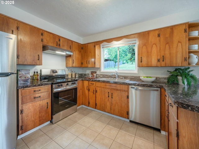 2625 Potter St, Eugene, OR 97405 - kitchen with appliances with stainless steel finishes, under cabinet range hood, a sink, brown cabinetry, and dark stone countertops