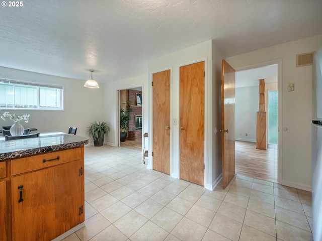 2625 Potter St, Eugene, OR 97405 - kitchen with light tile patterned floors, dark stone counters, baseboards, and brown cabinetry