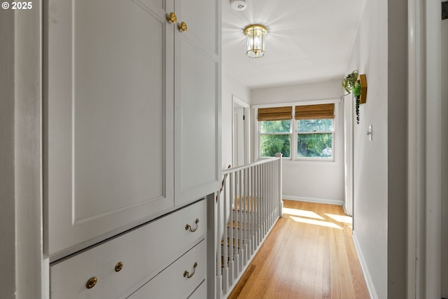 hall featuring light wood-style flooring and baseboards