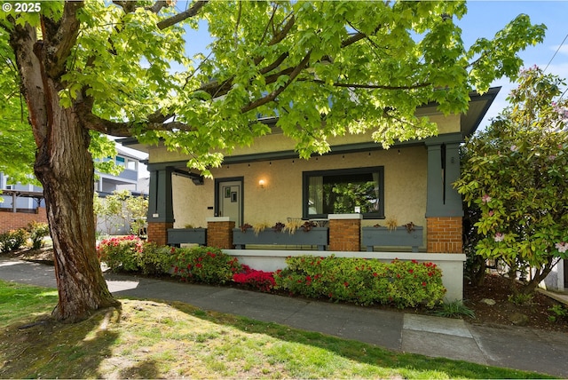 view of front facade featuring covered porch, brick siding, and stucco siding