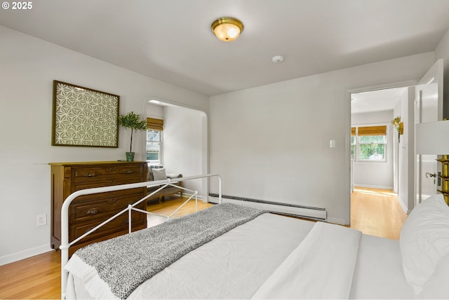 bedroom featuring baseboard heating, wood finished floors, and baseboards