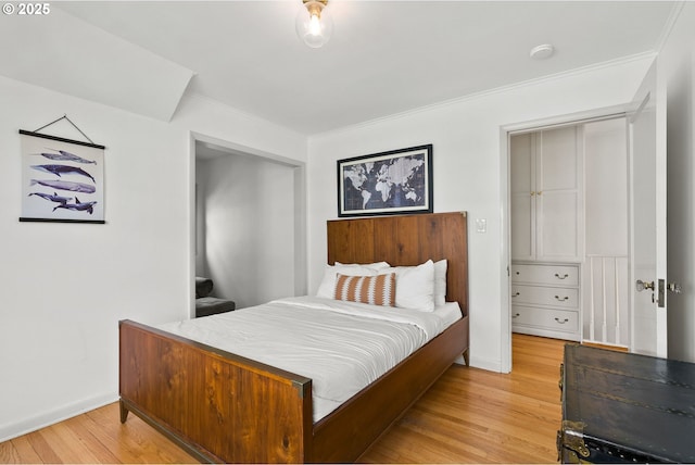 bedroom with light wood-style flooring, crown molding, and baseboards