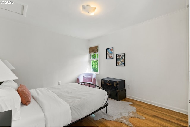 bedroom featuring wood finished floors, baseboards, and attic access