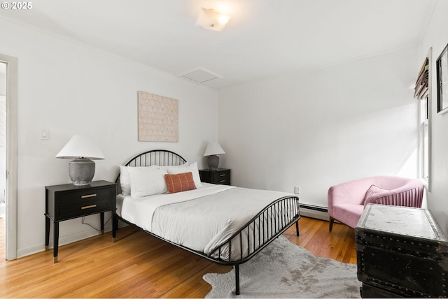 bedroom with attic access, wood finished floors, and a baseboard radiator