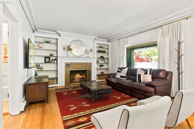 living area with wood finished floors, crown molding, a fireplace, a baseboard heating unit, and built in shelves