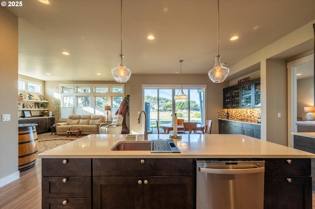 kitchen with an island with sink, decorative light fixtures, dishwasher, and sink