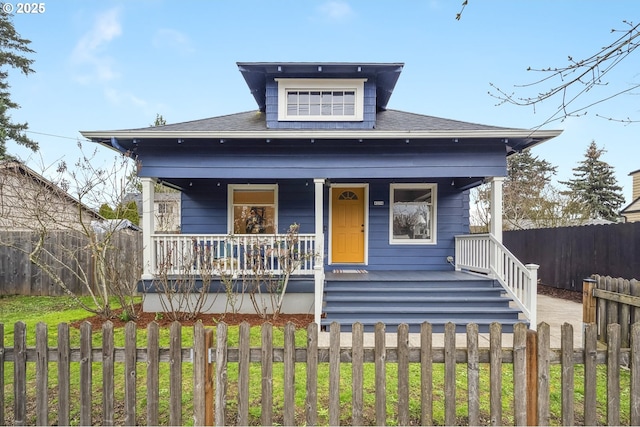 bungalow-style home featuring a fenced front yard and covered porch