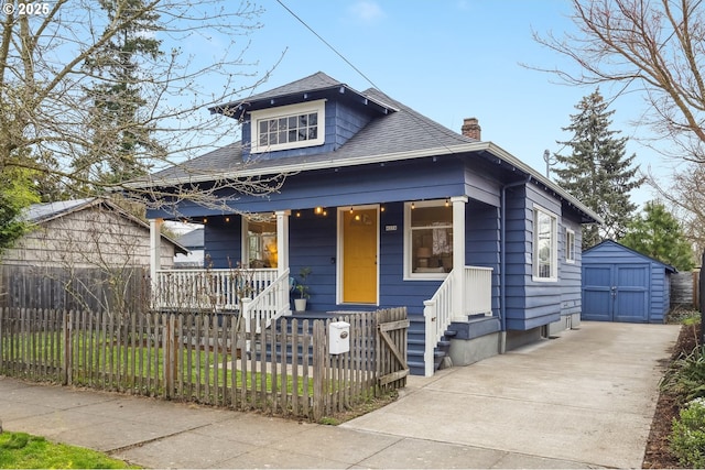 bungalow featuring roof with shingles, a porch, a chimney, a storage unit, and a fenced front yard