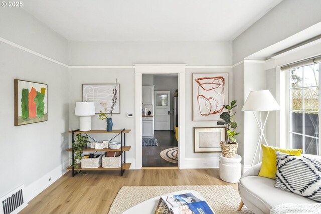 sitting room with visible vents, baseboards, and wood finished floors