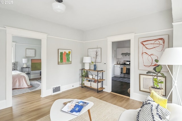 sitting room with light wood-style flooring, baseboards, and visible vents