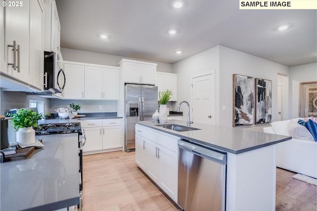 kitchen featuring stainless steel appliances, white cabinetry, sink, and a center island with sink