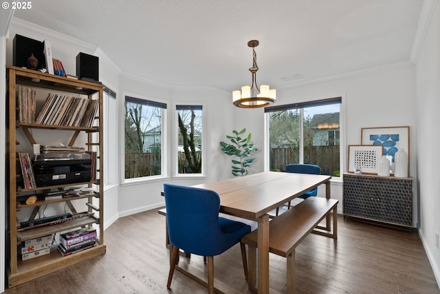 dining space with ornamental molding, a textured ceiling, a notable chandelier, and dark hardwood / wood-style floors