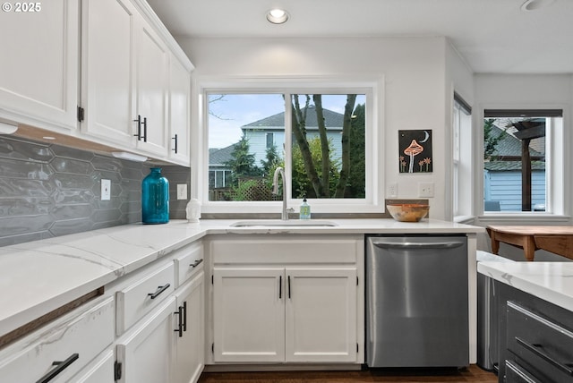 kitchen featuring white cabinets, light stone countertops, sink, stainless steel dishwasher, and backsplash