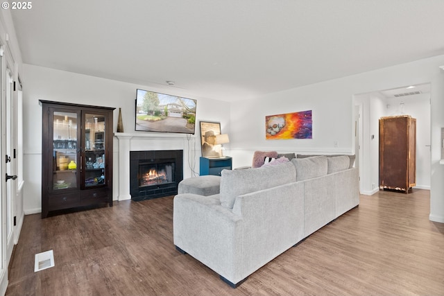 living room with wood-type flooring and a tiled fireplace