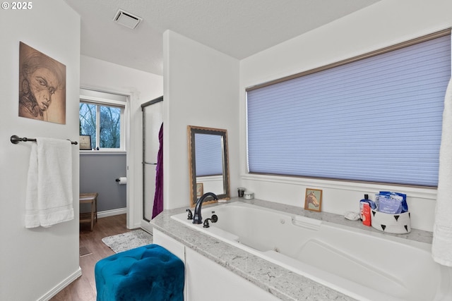 bathroom featuring a textured ceiling, hardwood / wood-style floors, and plus walk in shower