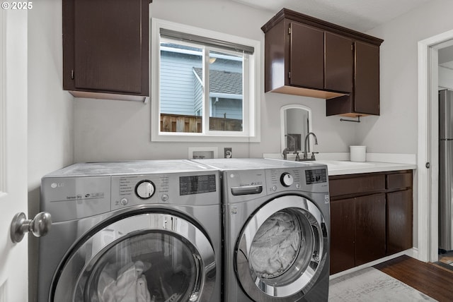 laundry room featuring sink, washer and clothes dryer, and cabinets