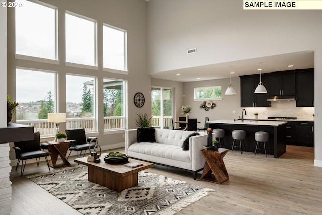 living room featuring sink, light hardwood / wood-style floors, and a high ceiling