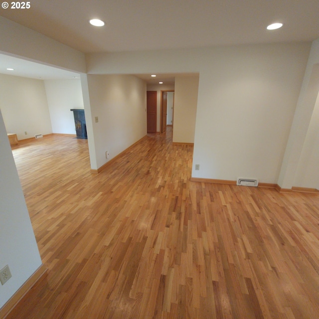 empty room featuring light wood-type flooring, baseboards, a fireplace, and recessed lighting