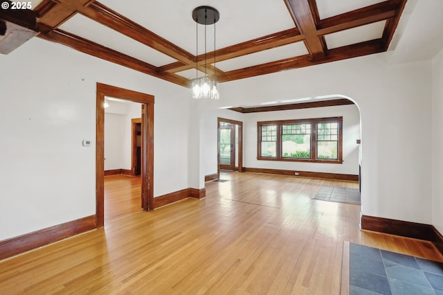 spare room featuring beam ceiling, an inviting chandelier, light hardwood / wood-style floors, and coffered ceiling